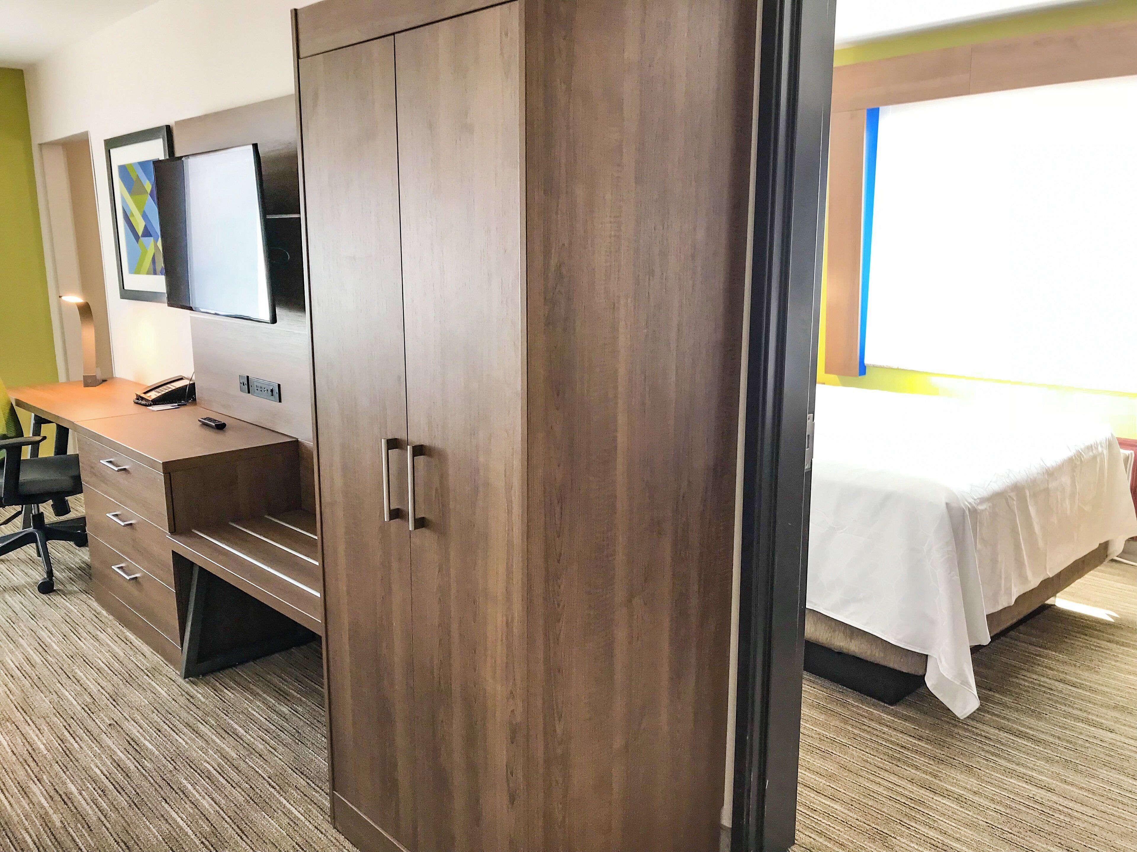 Habitación de hotel con una cama, un escritorio con teléfono y un armario.