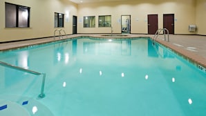 An indoor swimming pool with clear water, surrounded by beige walls and doors. - Holiday Inn Express & Suites Lubbock West by IHG (Lubbock)