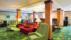 A hotel lobby with a red sofa, green armchairs, and a patterned carpet.