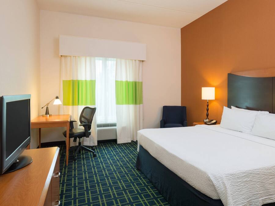 Une chambre d’hôtel équipée d’un lit, d’un bureau, d’une chaise, d’une télévision et d’une lampe.