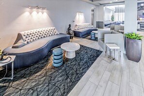 A modern lounge area with a curved sofa, a round coffee table, and a seating area with a bench and chairs. - Holiday Inn Express Hotel & Suites Columbus Univ Area - Osu by IHG (Columbus)