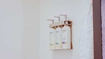 A bathroom with three Dove shampoo bottles on a wall-mounted shelf.