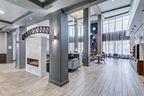 Un hall espacioso con chimenea, zona de estar y grandes ventanales.