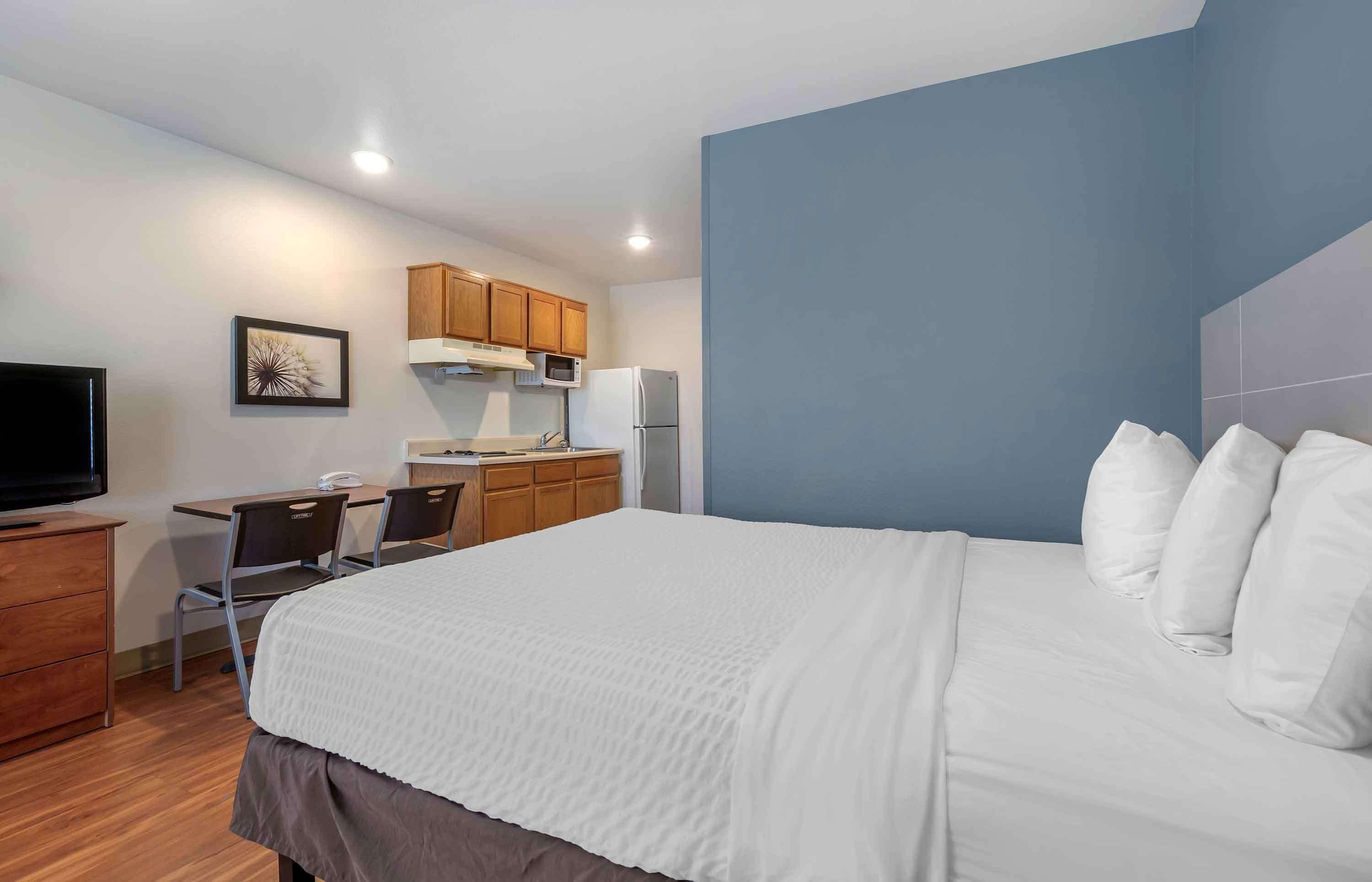 Une chambre d’hôtel comprenant un lit, un bureau avec une chaise, une télévision et une kitchenette.