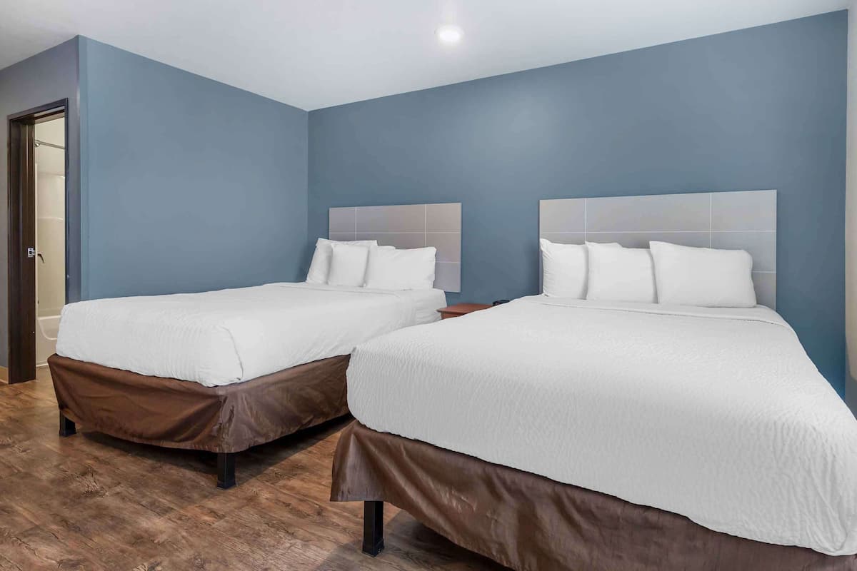 A hotel room with two beds, wooden flooring, and blue walls.