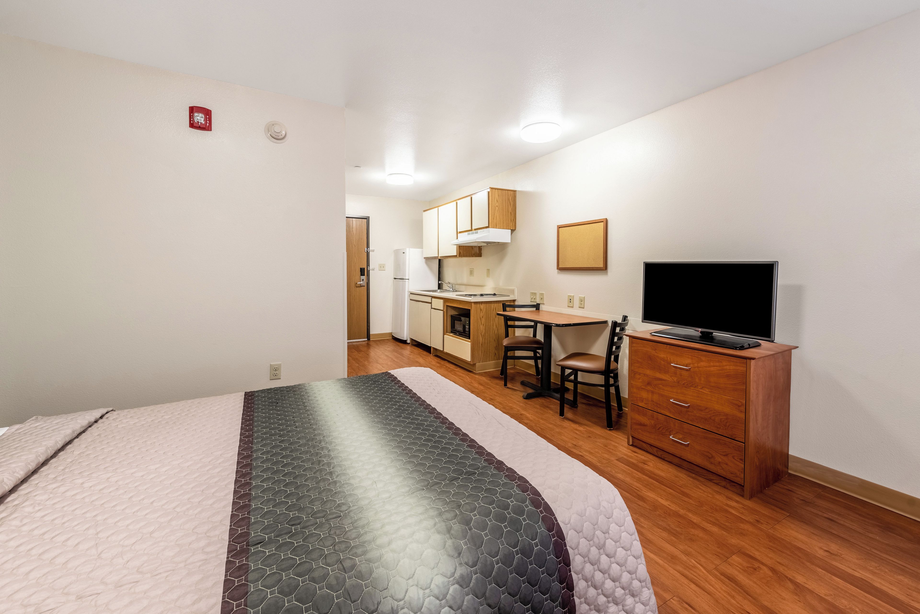 A hotel room with a bed, a desk, a chair, a television, and a wardrobe.
