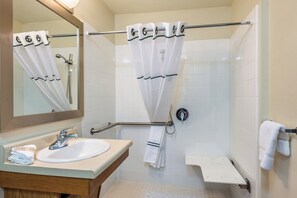 Une salle de bain équipée d’un lavabo, d’un miroir, d’une douche et d’un porte-serviettes.