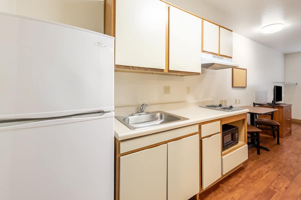 A kitchen with a white refrigerator, stainless steel sink, wooden cabinets, and a microwave.