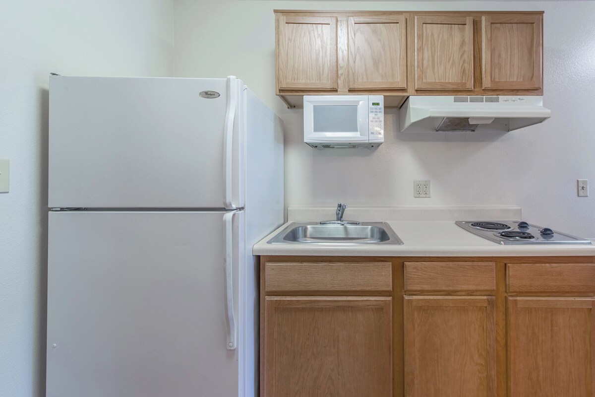 A kitchen with a refrigerator, microwave, stove, and wooden cabinets.