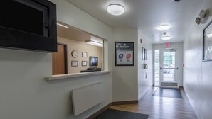 Een hotel receptie met een receptiebalie, een klok, ingekaderde certificaten en een bordje voor Home Towne Studios & Suites.