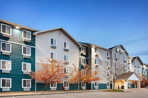 A multi-story hotel with a flat roof, large windows, and a covered entrance. - WoodSpring Suites Council Bluffs (Council Bluffs)
