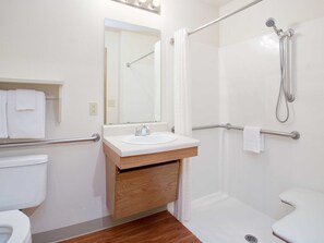 A modern bathroom with a white sink, mirror, and toilet. - WoodSpring Suites Council Bluffs (Council Bluffs)
