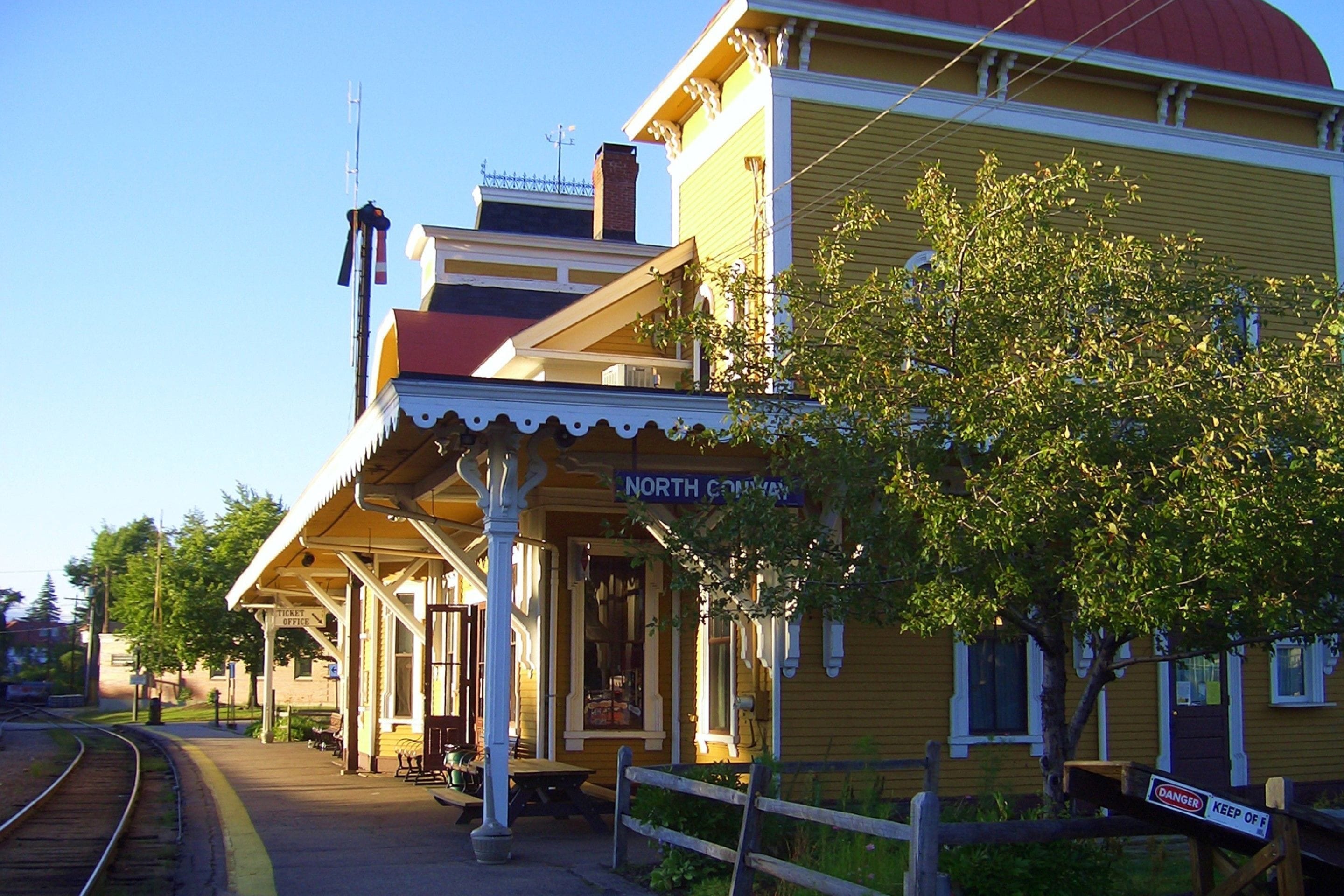 A yellow building with a red roof, a covered platform, and a sign reading "NORTH COVERTY".