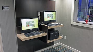 A business center with two computer workstations, a printer, and a window with a view of the outside.