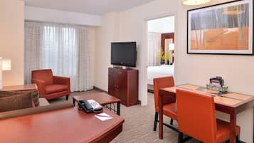 Une chambre d’hôtel équipée d’une télévision, d’un bureau, de deux chaises, d’un téléphone et d’un lit.