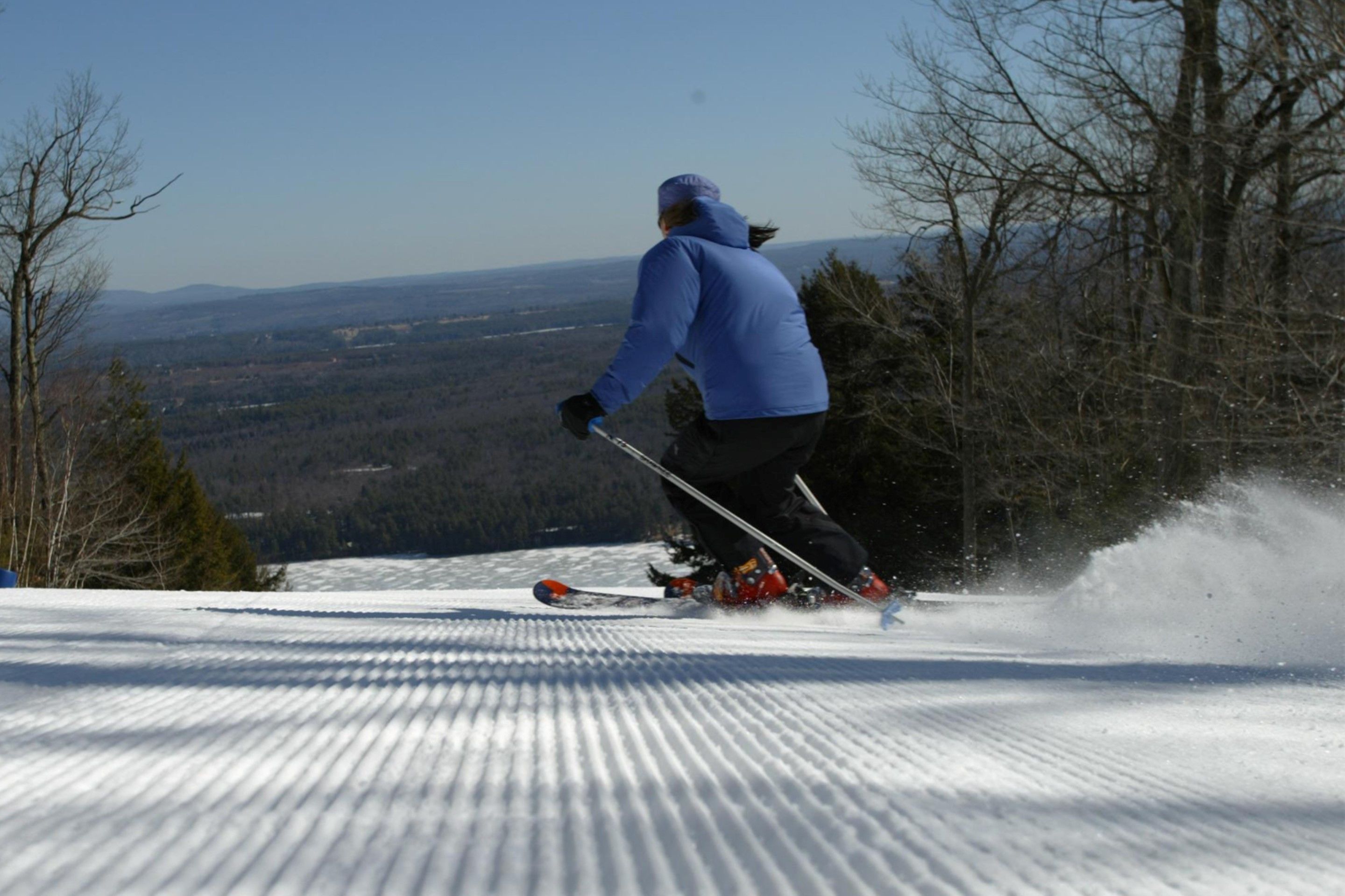 A person skiing on a snowy slope with a clear view of the surrounding landscape.