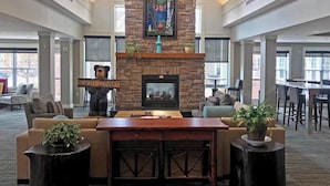 A spacious lobby with a stone fireplace, comfortable seating, and a sign indicating the direction to the North Corridor. - Residence Inn by Marriott, North Conway (North Conway)