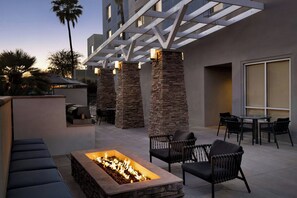 An outdoor patio area with a fire pit, stone pillars, and outdoor seating. - TownePlace Suites by Marriott Goodyear (Goodyear)