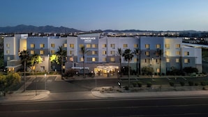 Ein mehrstöckiges Hotel im modernen Design, mit Parkplatz und Blick auf die Berge im Hintergrund.