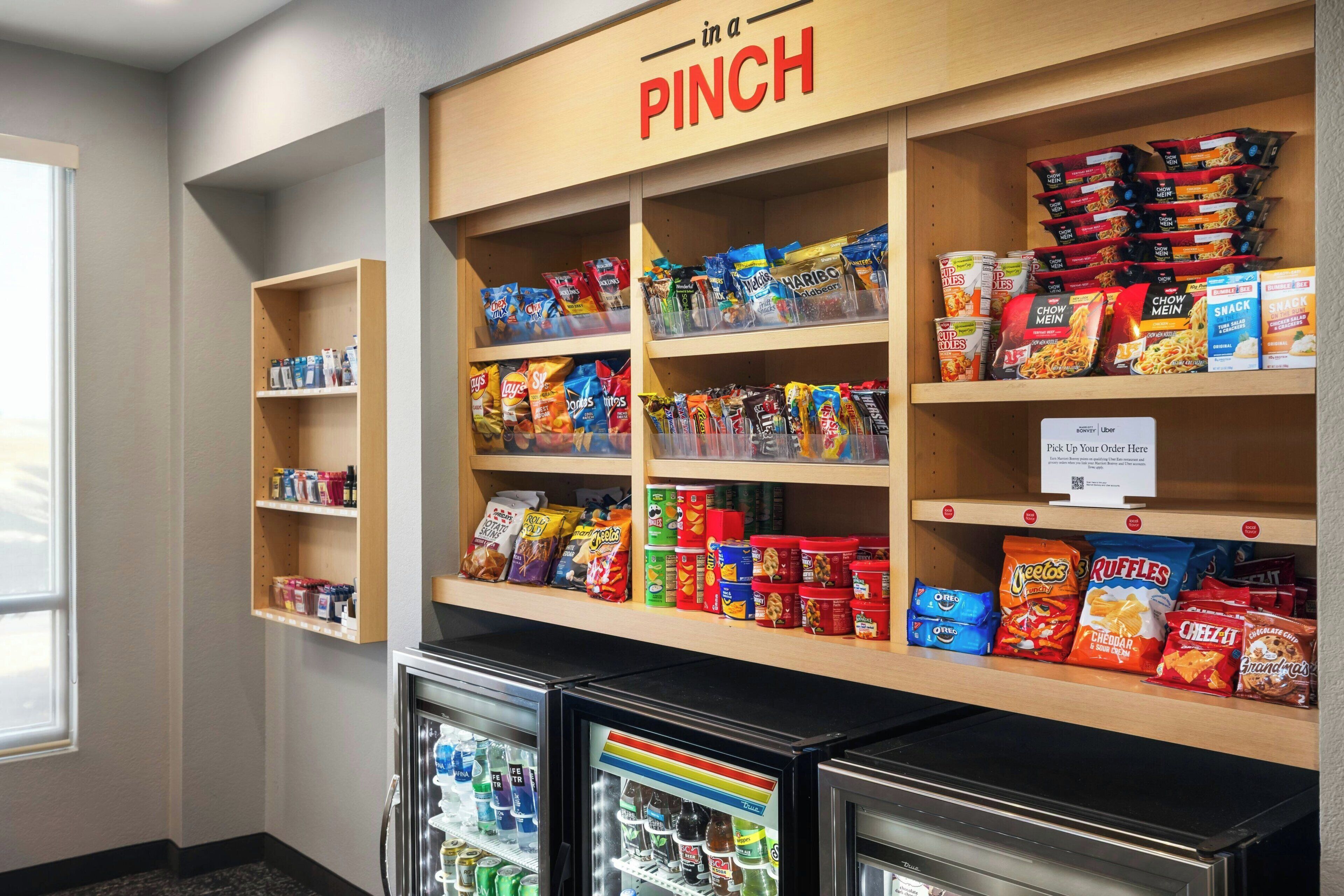 A snack and beverage display in a room with shelves and refrigerators.