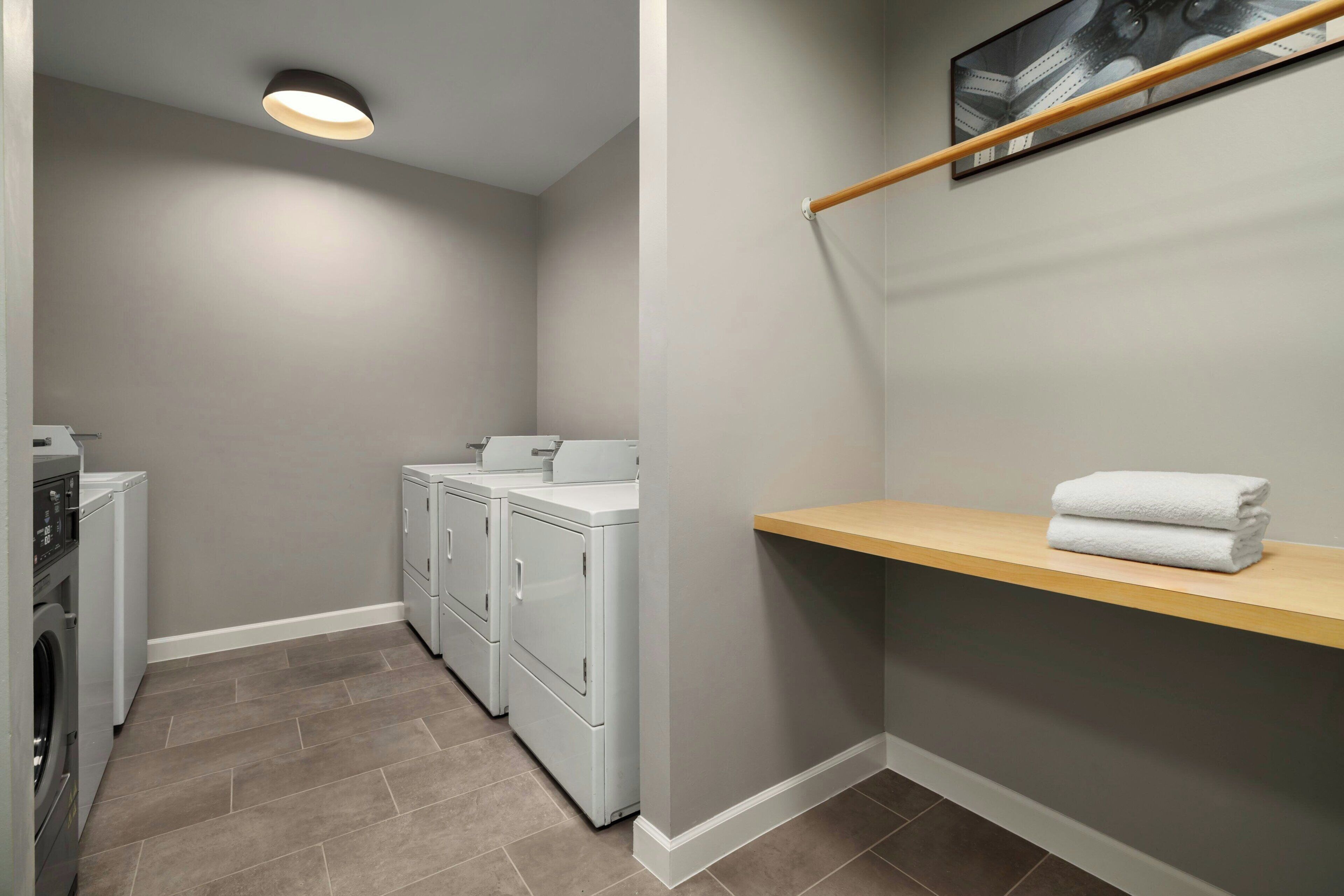 A laundry room with a washing machine, dryer, and a shelf with folded towels.