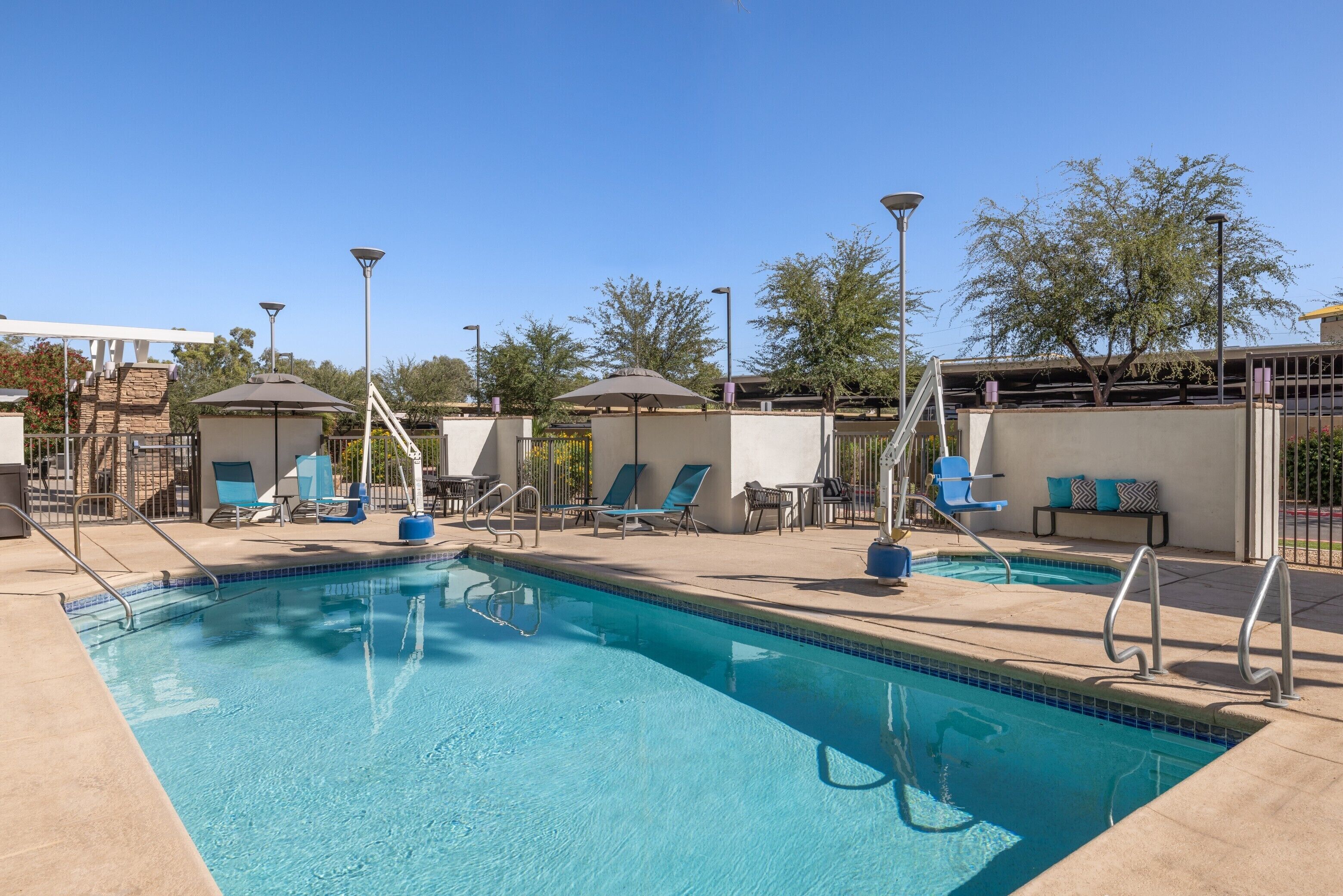 Una piscina al aire libre, sombrillas, sillones reclinables de piscina