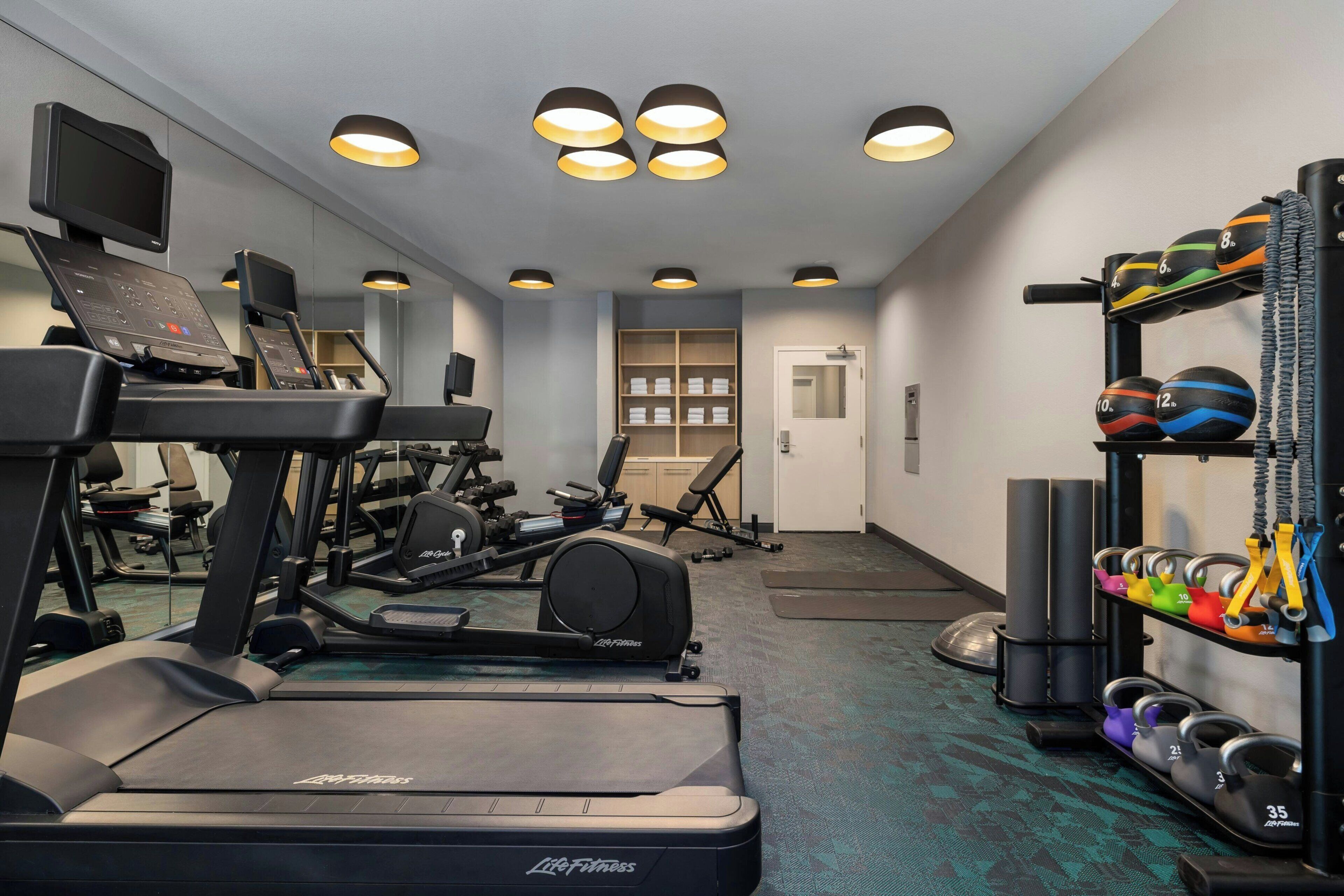 Un gimnasio con cintas de correr, pesas y pelotas de ejercicio.