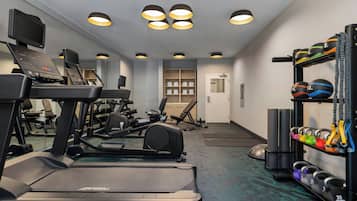 Un gimnasio con cintas de correr, pesas y pelotas de ejercicio.