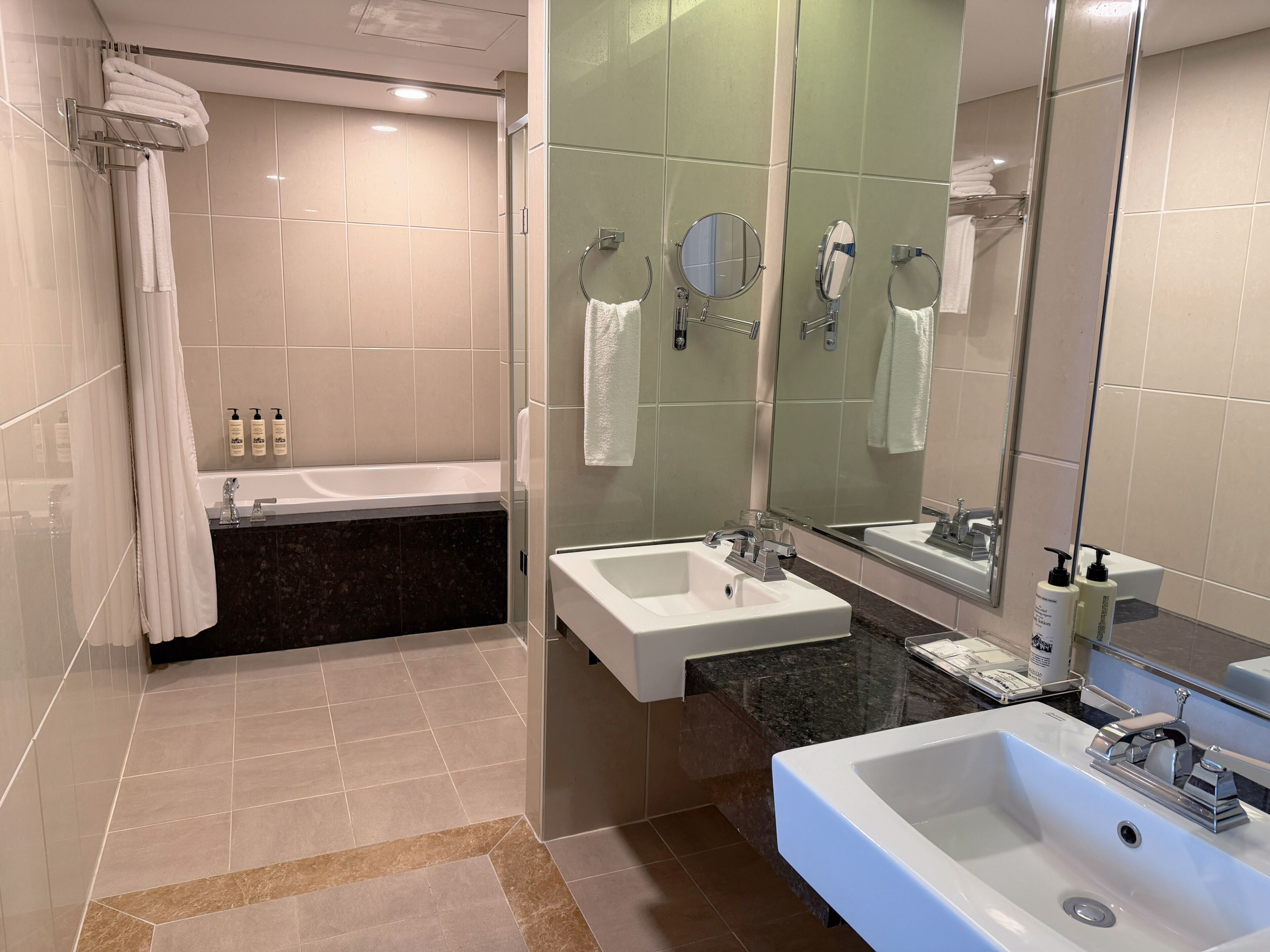 Ein modernes Badezimmer mit Badewanne, zwei Waschbecken und einem großen Spiegel.