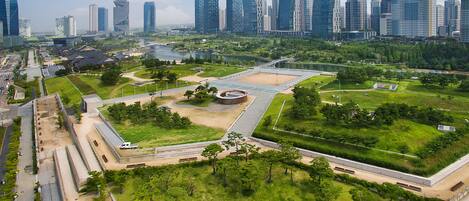 A modern urban park with green spaces, pathways, and a central circular plaza.