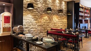 A restaurant with a stone wall, buffet, and seating area. - Hotel Les Théâtres (Paris)