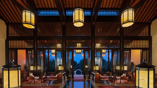 A traditional-style lobby with wooden paneling, large lantern-style lights, and a central pathway leading to a view of a pagoda. - Banyan Tree Hangzhou (Hangzhou)