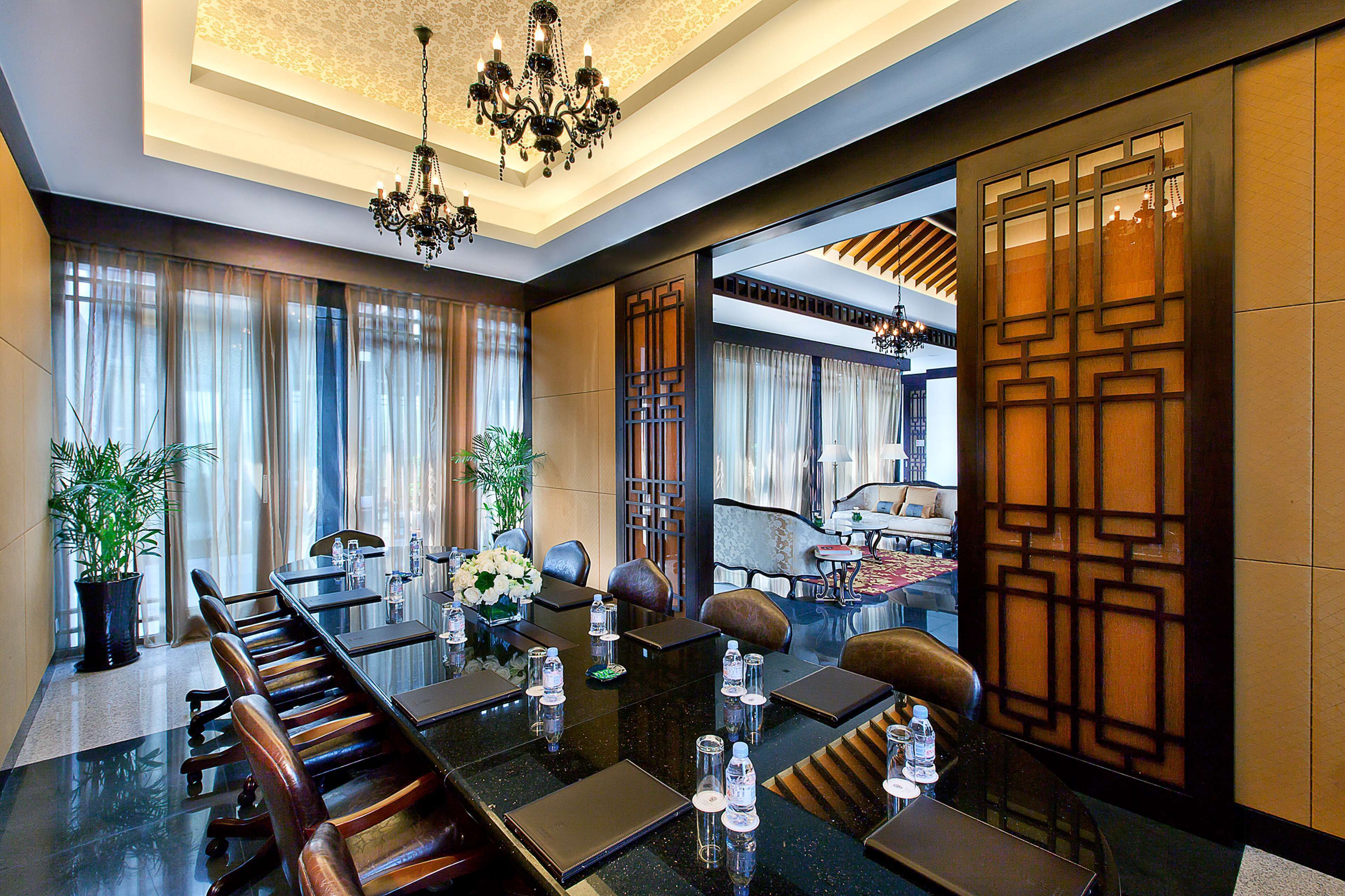 Uma sala de conferência com uma mesa comprida, cadeiras e um candelabro.