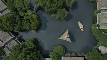 An aerial view of a river with boats, surrounded by dense greenery and traditional buildings.