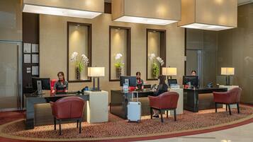 A hotel reception area with a modern design, featuring a reception desk, computers, and seating for guests.