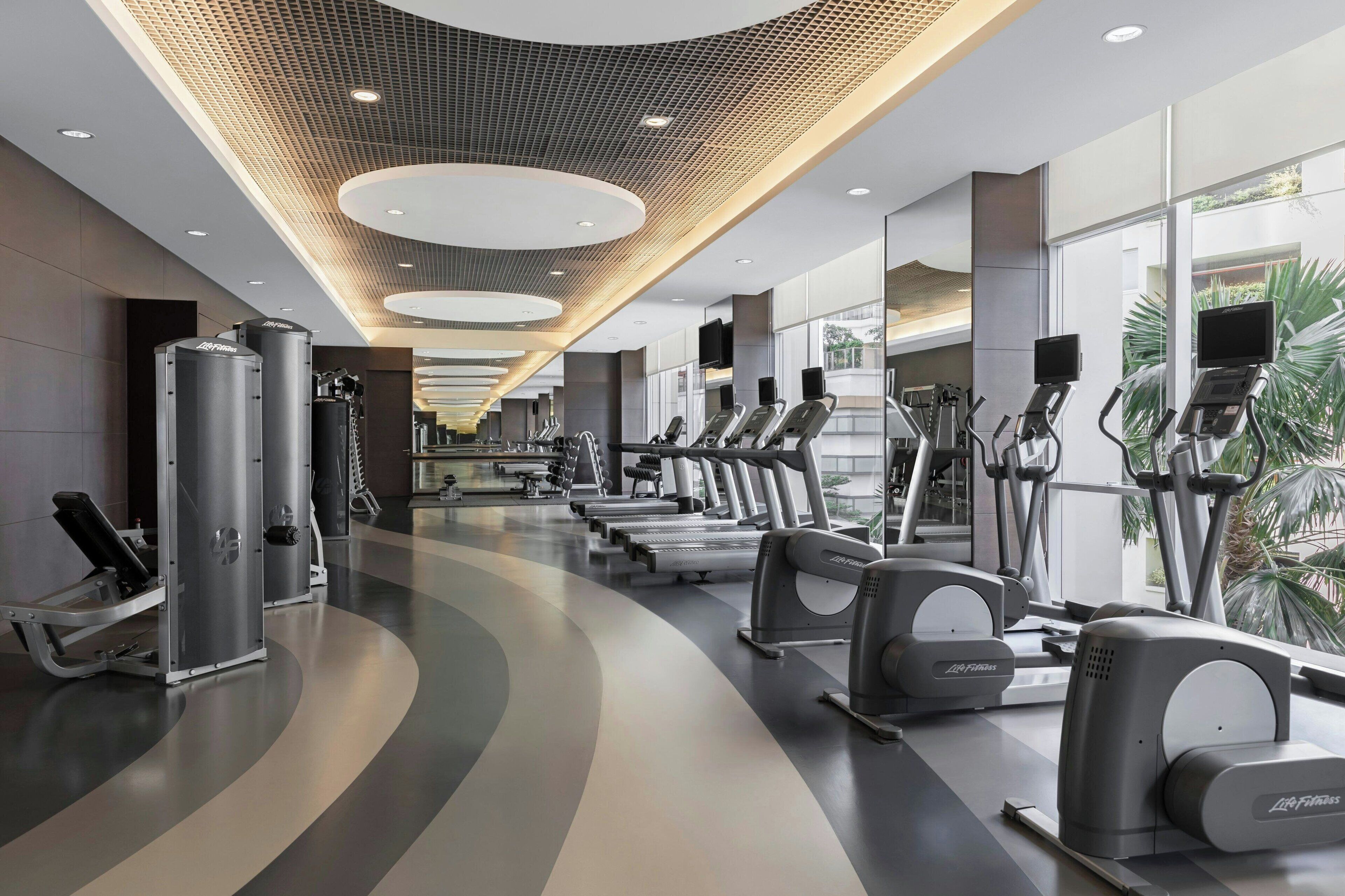 Un gimnasio moderno con cintas de correr, elípticas y máquinas de pesas.