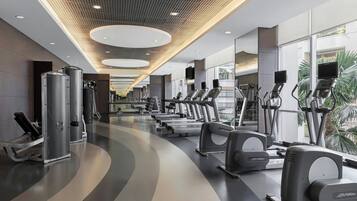 Un gimnasio moderno con cintas de correr, elípticas y máquinas de pesas.
