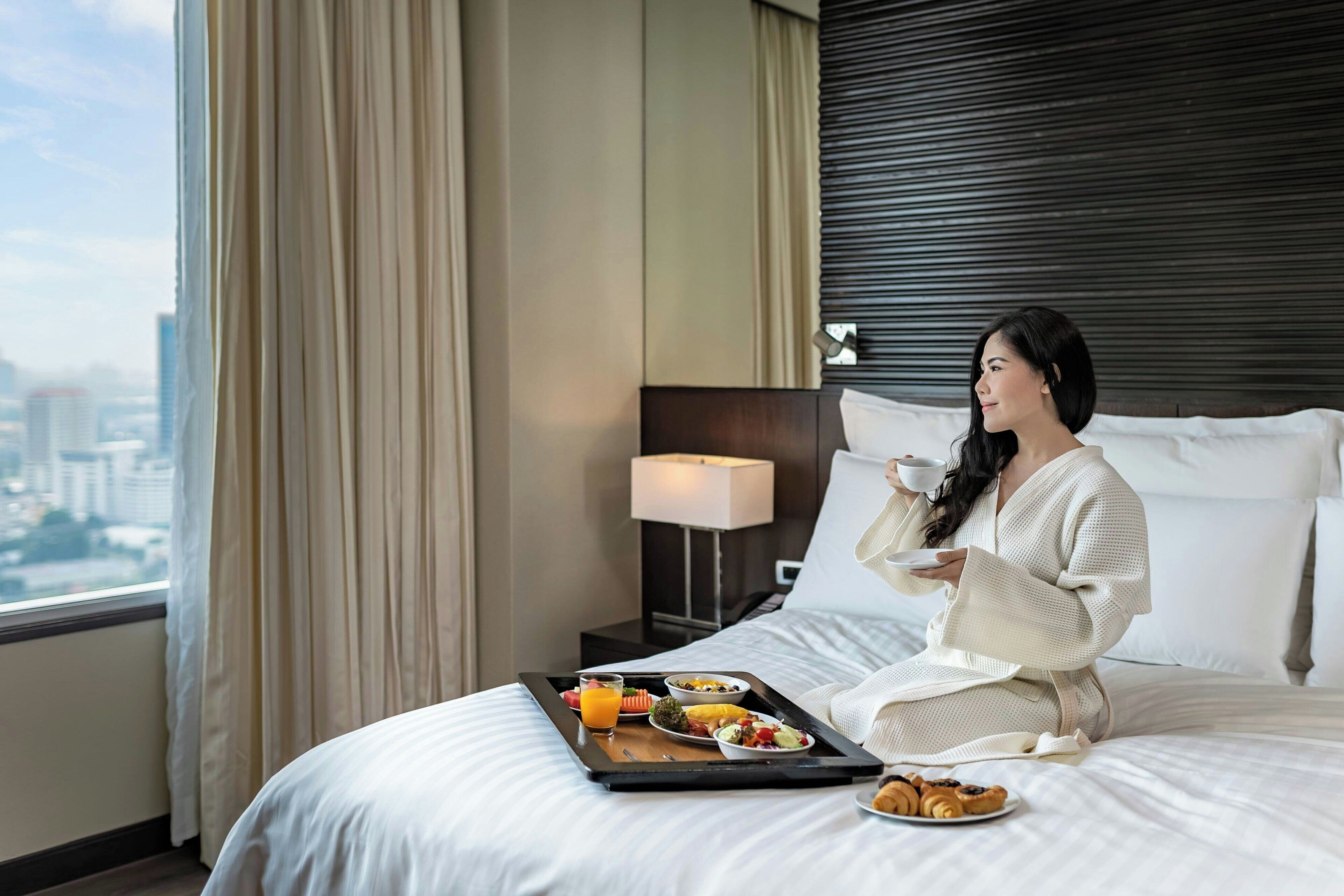 Una habitación de hotel con una cama, una bandeja con artículos de desayuno y vistas a la ciudad.