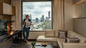 A modern living room with a large window, a sofa, a coffee table, and a TV. - Marriott Executive Apartments Sukhumvit Park, Bangkok (Bangkok)