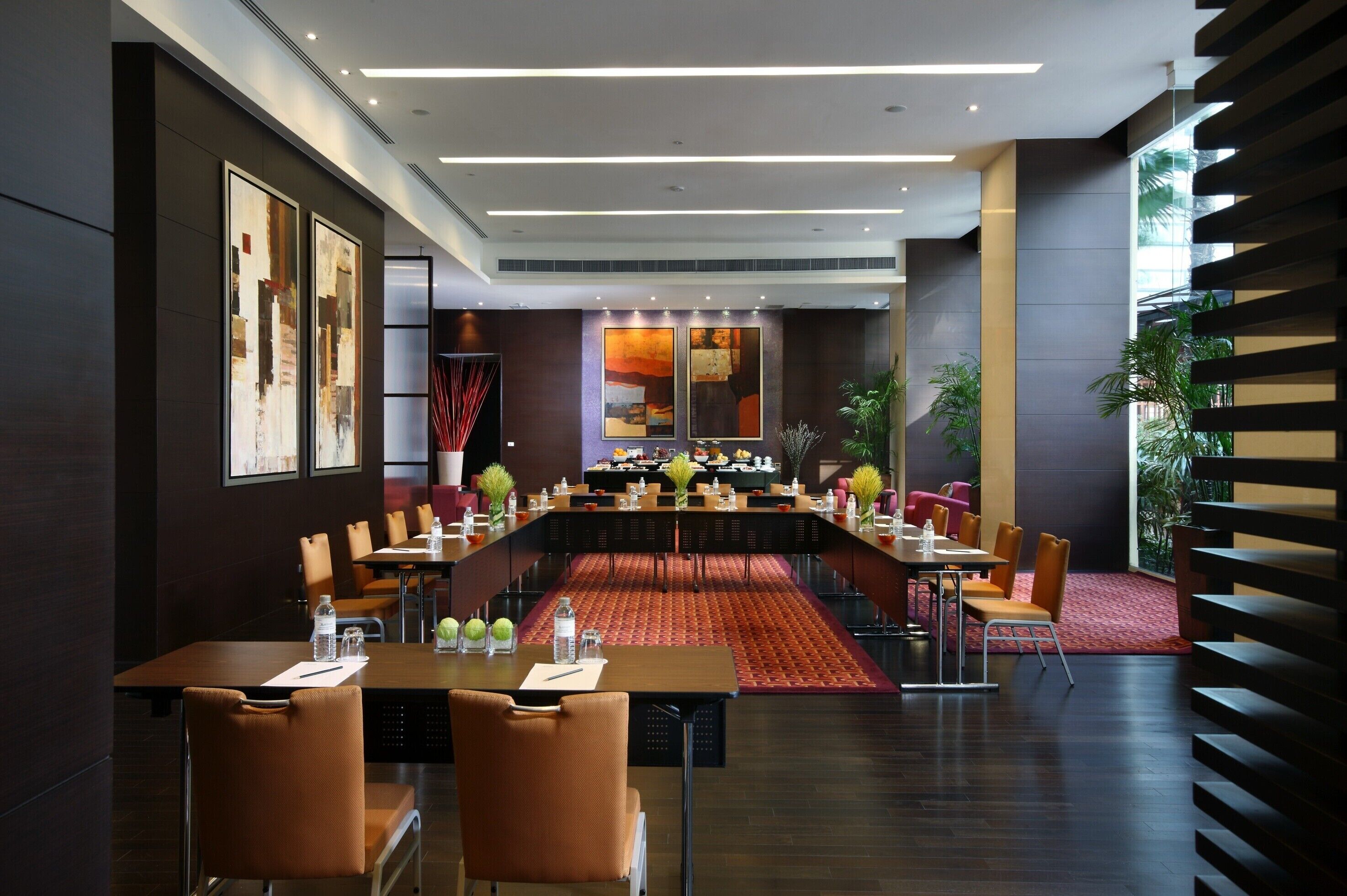 A modern conference room with a long table, multiple chairs, and a red carpet.