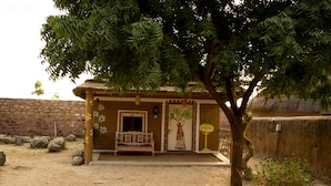 Un bâtiment traditionnel avec un toit de chaume, un banc à l’extérieur et un arbre devant.