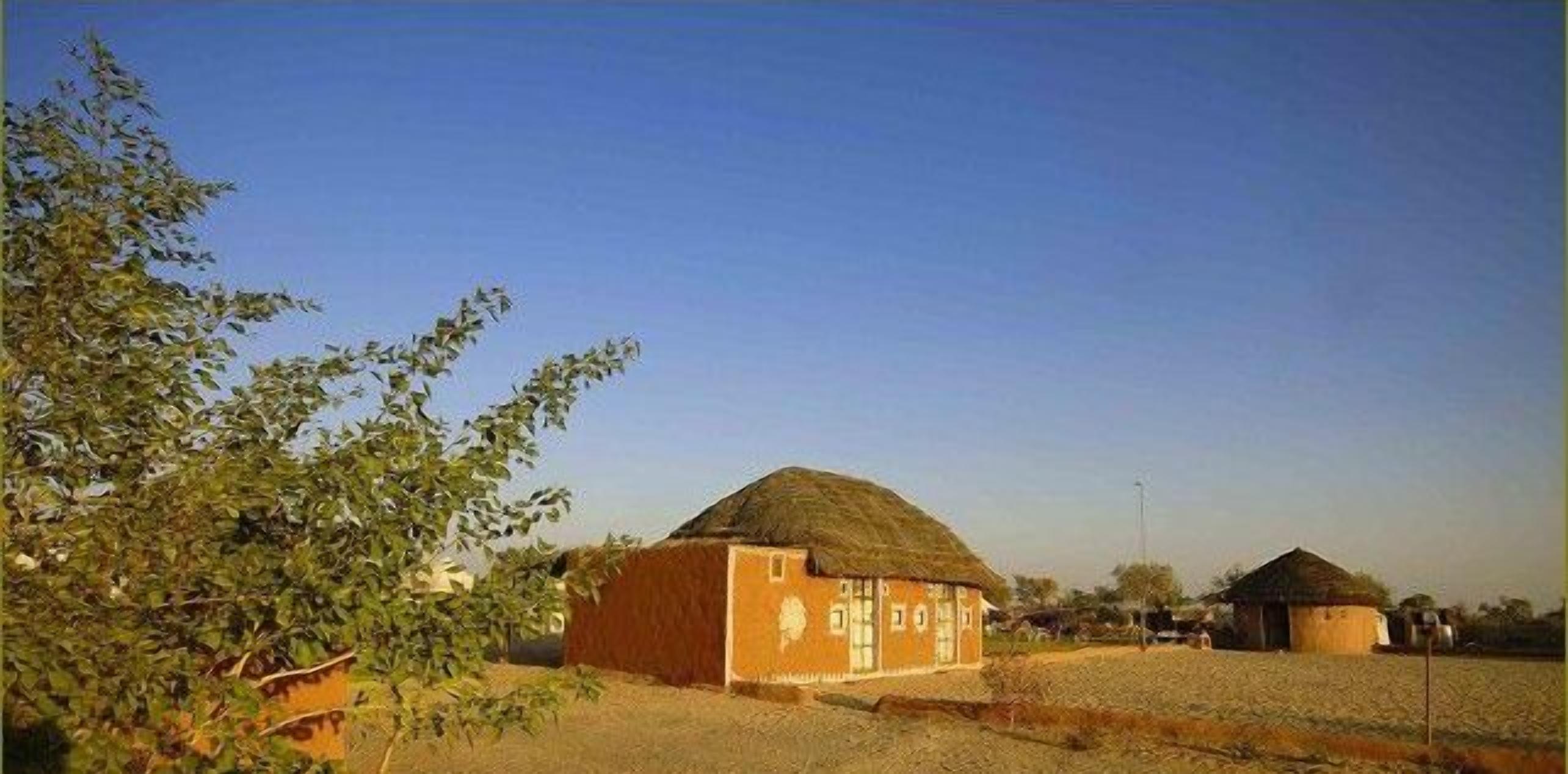 Entorno rural con una casa de techo de paja y un edificio más pequeño al fondo.