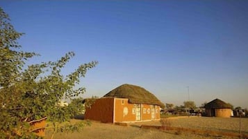Entorno rural con una casa de techo de paja y un edificio más pequeño al fondo.