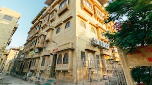A multi-story building with traditional architecture, featuring balconies, large windows, and air conditioning units. - Hotel Fifu (Jaisalmer)
