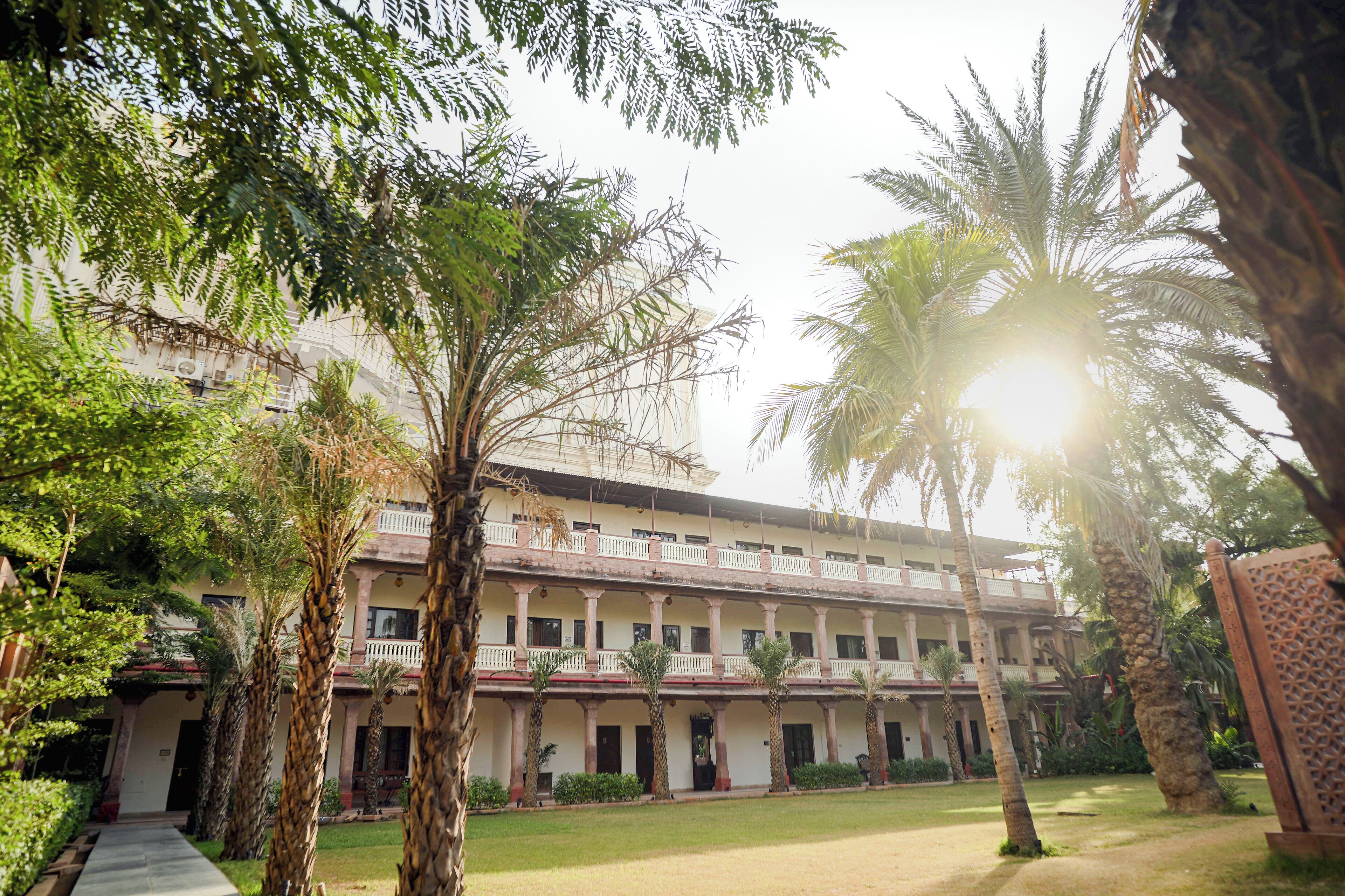 A multi-story building with a central courtyard, surrounded by palm trees and other greenery.