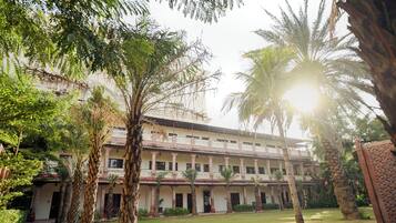A multi-story building with a central courtyard, surrounded by palm trees and other greenery.
