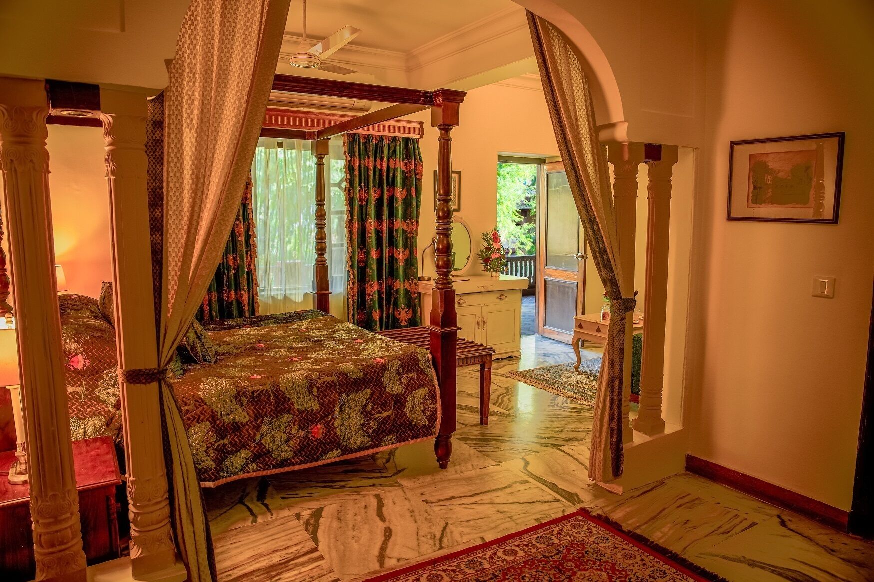 A bedroom with a four-poster bed, a chandelier, and a view of the outdoors.