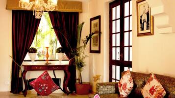 A living room with a sofa, a table, a chandelier, and a window with curtains.