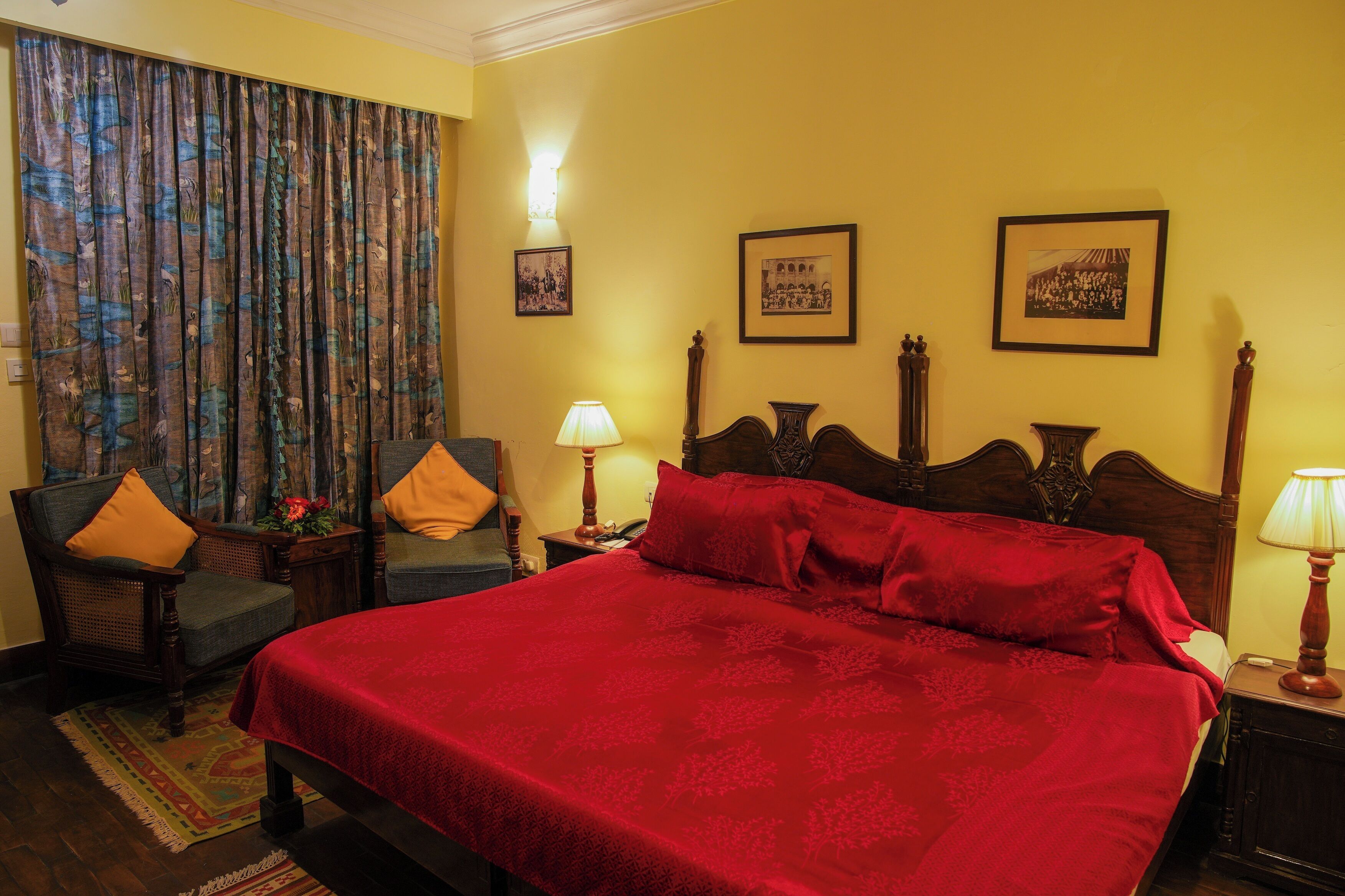 Une chambre d’hôtel avec un grand lit, deux chaises, une table de chevet et des lampes fixées au mur.