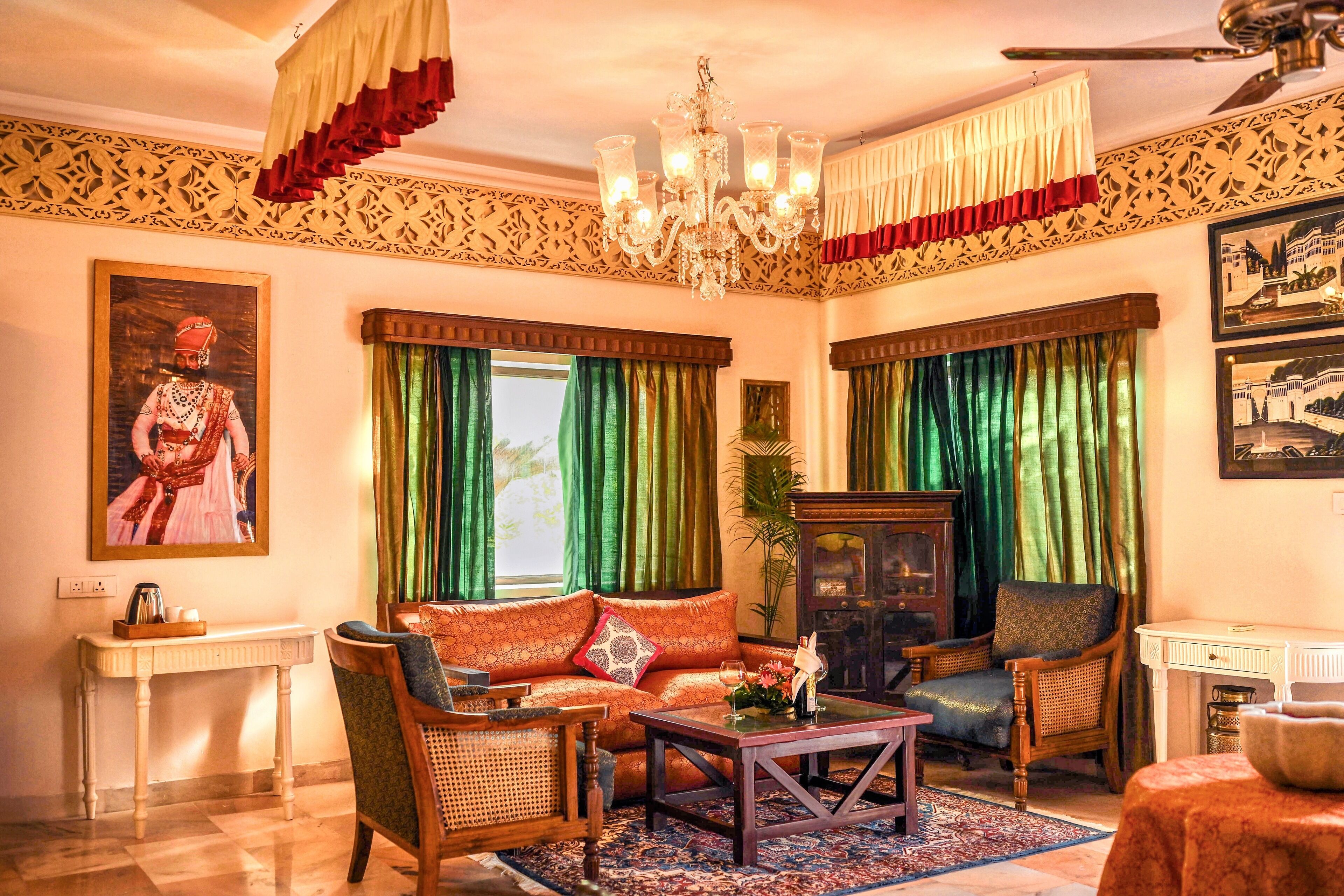 A traditional living room with a sofa, chairs, a coffee table, a chandelier, and a large painting on the wall.